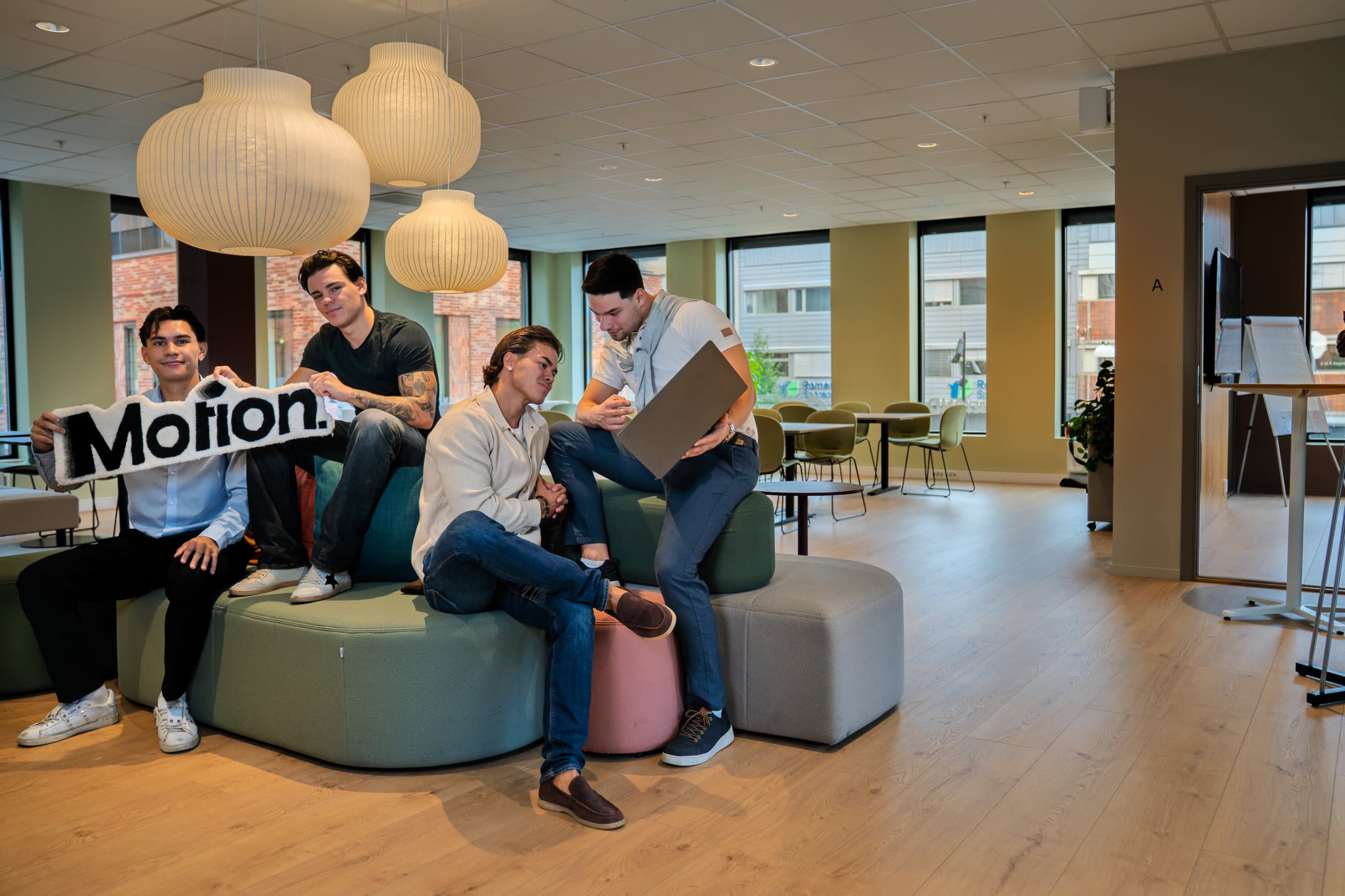 Teamet i Motion Media AS på kontoret, med Motion-skiltet